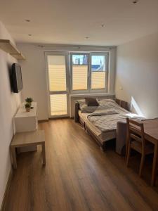 a bedroom with a bed and a table and two windows at Zamkowa18 in Pabianice