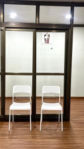 two white chairs in a room with windows at Casa Zo an entire fully furnished apartment in Āīzawl