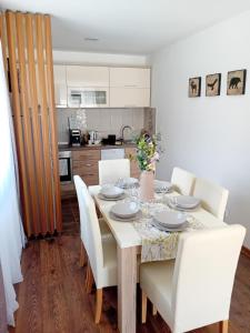 a dining room table with white chairs and a kitchen at Durmitor Sunstone in Žabljak +15 photos