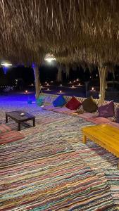 a room with a rug and tables and a straw umbrella at La Basha Camp in Dahab