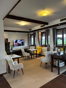 a living room with tables and chairs and a tv at Serenity Residence Hotel & Wellness in Liptovský Trnovec