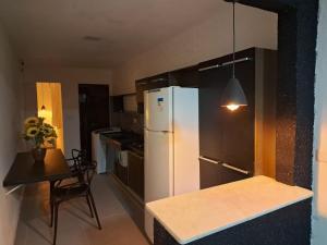 a kitchen with a white refrigerator and a table at espaço completo só para você e seus familiares in Gravatá
