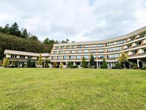 a large building with a grass field in front of it at Apartmán Všemina 346 in Všemina