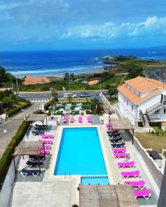 Blick auf einen Pool, Liegestühle und das Meer in der Unterkunft Hotel Marola in A Lanzada