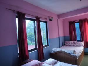 a bedroom with two beds and two windows at Hotel Devi's Fall View in Pokhara