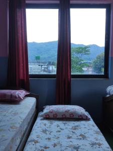 a bedroom with two beds and a large window at Hotel Devi's Fall View in Pokhara