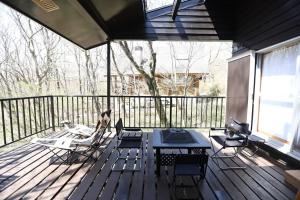 a porch with a table and chairs on a deck at 木漏れ日の森で都会では味わえない静寂を那須の自然を満喫する貸別荘つつじ山 in Nasu