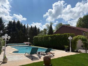 a swimming pool with two lawn chairs and a table at Les Lodges de la Moivre in Saint-Jean-sur-Moivre