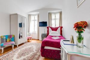 a small bedroom with a pink bed and a table at Prague Siesta Apartments in Prague