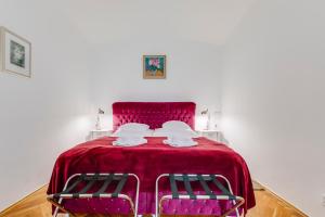 a bedroom with a red bed with two chairs at Prague Siesta Apartments in Prague
