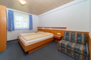 a small bedroom with a bed and a chair at Haus Muntschnei in Sankt Gallenkirch