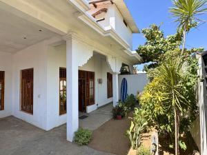 a white house with trees and plants in front of it at ThePopos in Arugam Bay