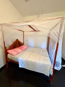a bed with a canopy in a room at ThePopos in Arugam Bay