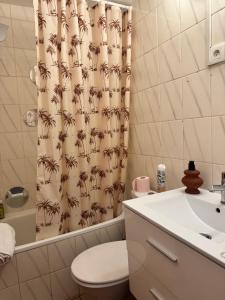 a bathroom with a shower curtain with a toilet and a sink at Studio Centre Strasbourg in Strasbourg +27 photos