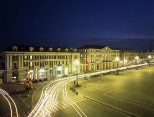 una strada di città di notte con edifici e luci di Phi Hotel Principe a Cuneo