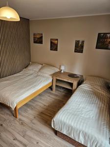 two beds in a room with a table at Pokoje DARMAT in Stegna