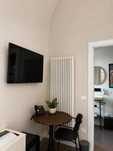 a room with a table and a television on a wall at Albergo Diffuso Ginevra Boutique Rooms - Palazzo Leosini - Residenze D'Epoca in LʼAquila