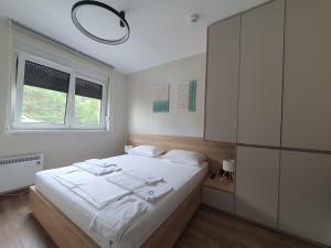 a bedroom with a white bed and a window at Omega Dom in Vrnjačka Banja