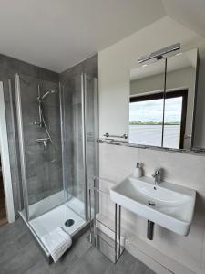 a white bathroom with a shower and a sink at Ferienwohnung Klahn Neue Tiefe in Neue Tiefe Fehmarn +3 photos