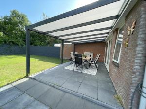 awning over a patio with a table and chairs at Het lila huisje in Herkingen