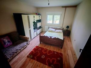 a bedroom with a bed and a couch and a window at HERC domaćinstvo in Nova Varoš