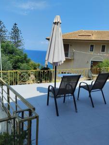 a patio with two chairs and an umbrella at REPANTALIA Apartment in Zakynthos