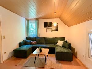 a living room with a green couch and a table at Ferienhaus Hirschglück in Alpirsbach