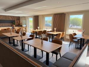 a restaurant with wooden tables and chairs and windows at Pinnø - Padel Hotel Food in Pinnow