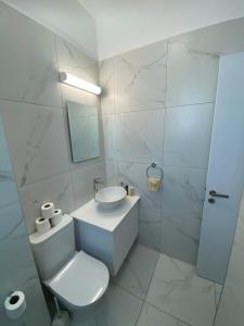 a white bathroom with a toilet and a sink at Sea view Penthouse Universal Residences in Paphos