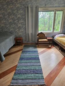 a bedroom with a rug on the floor and a window at Mänttä Tammirannantie in Mustalahti