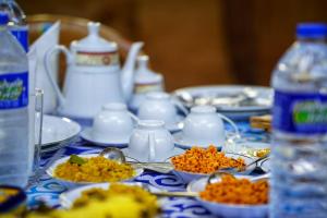 a table with plates of food and cups and spoons at The Travel Tree Hostel in Sigiriya