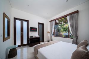 a bedroom with a bed and a window and a desk at Uluran Villa Uluwatu in Uluwatu