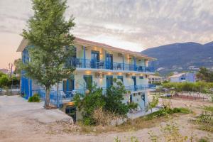 a large house with blue balconies and a tree at Akrotiri Vasiliki in Vasiliki