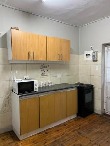 a kitchen with wooden cabinets and a black microwave at The Willow Whispers guest house in Gqeberha