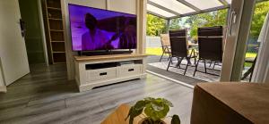 a living room with a tv and a table with chairs at Het lila huisje in Herkingen