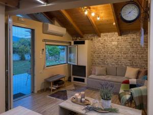 a living room with a couch and a clock on the wall at The Countryside Loft in Katsikás