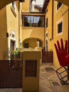 a patio with a red chair and a building at Albergo Diffuso Ginevra Boutique Rooms - Palazzo Leosini - Residenze D'Epoca in LʼAquila