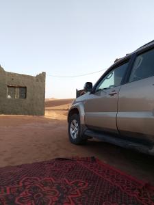 a car parked in front of a building in the desert at Camp la mer de sable in Mhamid