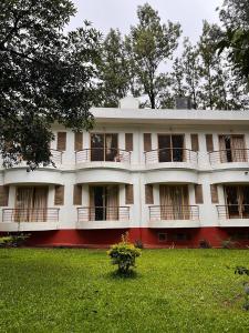 a large white building with a green yard at Nature Trinity House in Panchgani