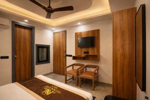 a bedroom with a bed and a chair and a tv at Hotel Airport Elite Suit Near Delhi Airport in New Delhi