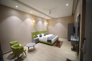a bedroom with a bed and a tv and a chair at Hotel Vantara in Karnāl