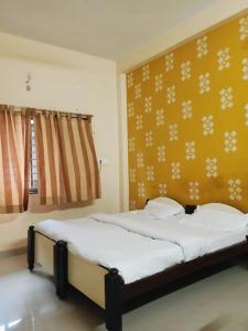 a bedroom with two beds and a yellow wall at Hotel MNP in Jabalpur
