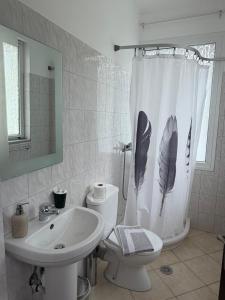 a bathroom with a toilet sink and a shower curtain with feathers at Hotel Iliana in Mandrotopos +25 photos