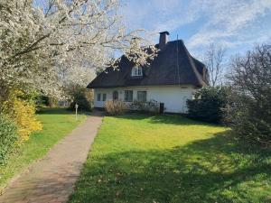 a white house with a thatched roof on a lawn at Reethüs am Klintumer Moor in Leck