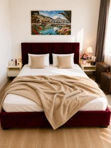 a bedroom with a large bed with a painting on the wall at Vasiliu Boutique Hotel Ksamil in Ksamil