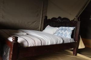 a wooden bed with pillows on it in a room at Elephant trails camp in Sekenani +50 photos