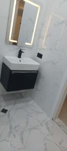 a white bathroom with a sink and a mirror at Apartament Tbilisi in Tbilisi City