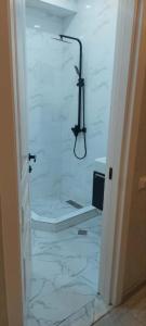a bathroom with a white marble floor with a shower at Apartament Tbilisi in Tbilisi City