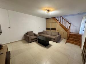 ein Wohnzimmer mit Sofa, Tisch und Treppe in der Unterkunft Catana in Arad + 1 Foto