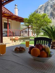 a plate of fruit on a table with orange juice at Emis house krioneri in Lapanayoí